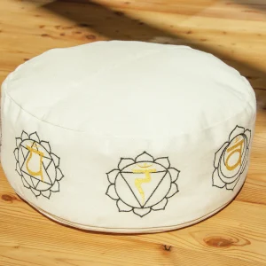 Helles Meditationskissen mit Stickereien der 7 Chakren auf Holzfußboden