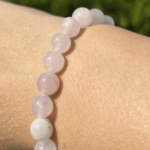 Detailansicht eines Rosenquarz Armbands am Handgelenk bei Sonnenschein