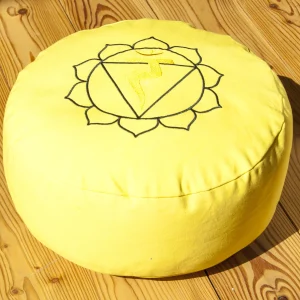Gelbes Meditationskissen mit Solarplexus-Chakra-Symbol auf Holzboden